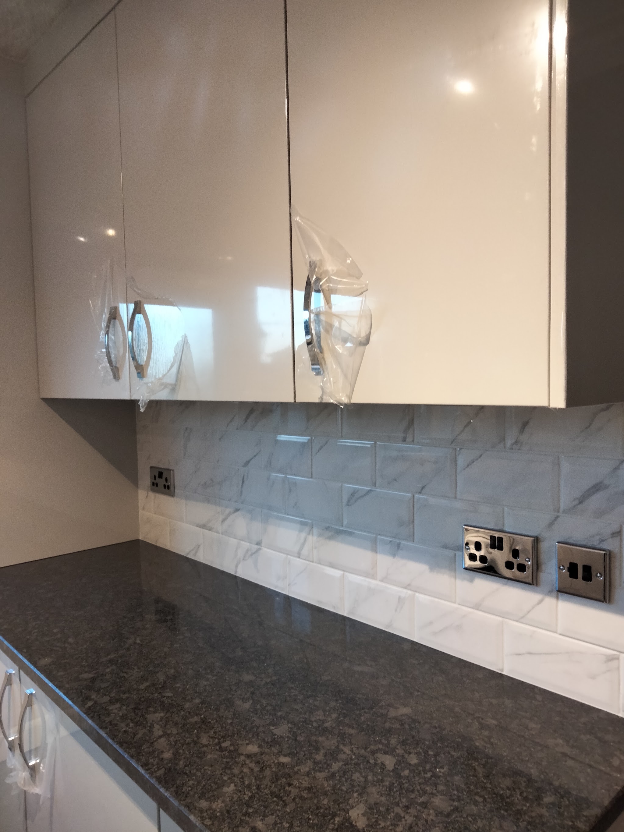 Close up of new gloss kitchen doors, still in their protective film, above a granite worktop